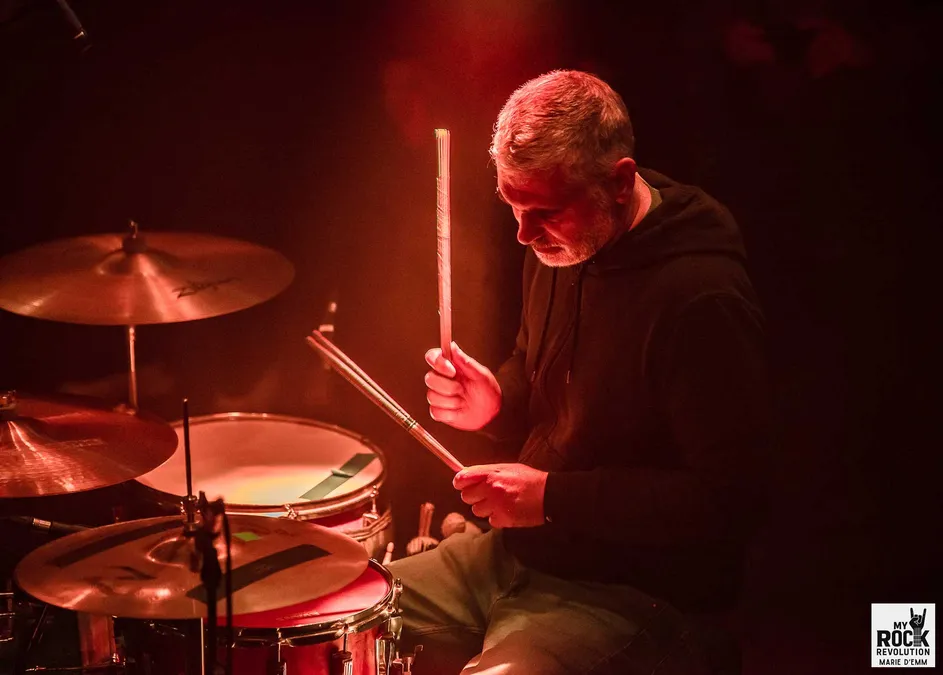 Grive – batteur dans une lumière rouge intimiste